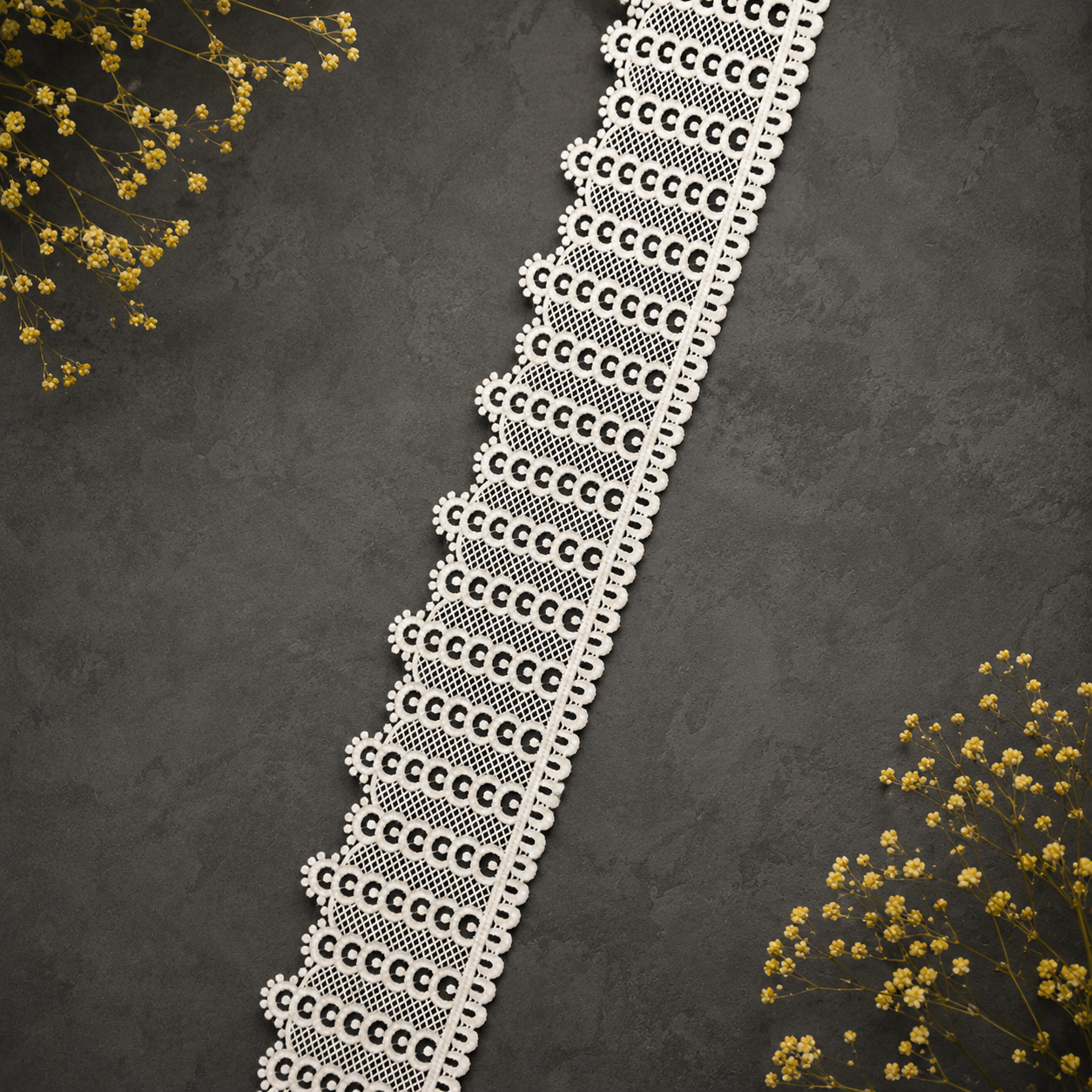 Decorative lace trim on a dark textured background with yellow flowers.