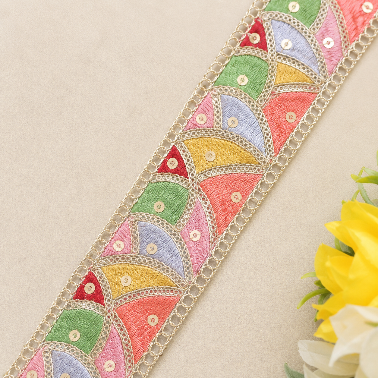 Colorful embroidered lace trim on a beige background with flowers.