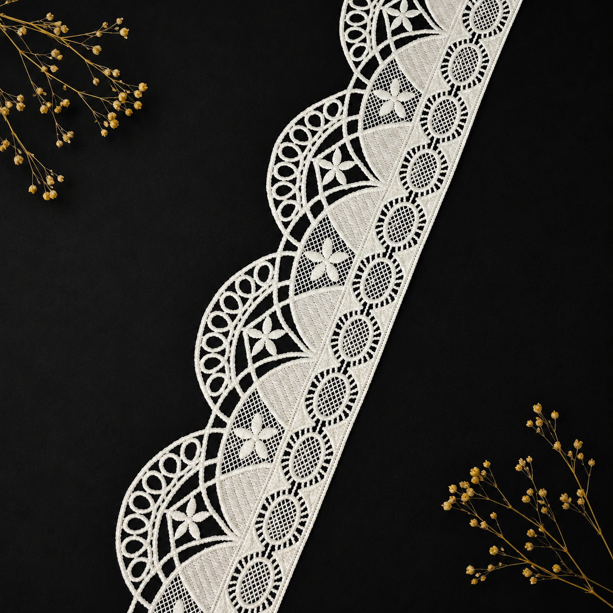 Decorative white lace ribbon on a black background with dried flowers.